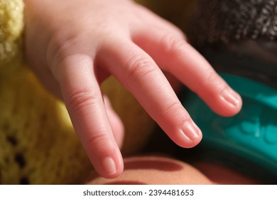 A close-up shot of the newborn baby's hand reaches out as if trying to hold something. - Shutterstock ID 2394481653