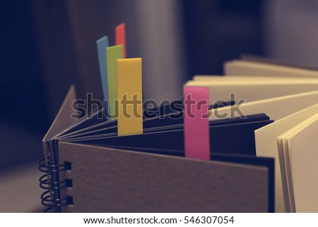Closeup shot of notebook with color note tab. Notebook with colors note tab on wooden table background, Vintage picture tone.

