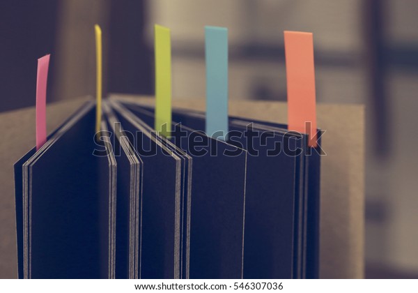 Closeup\
shot of notebook with color note tab. Notebook with colors note tab\
on wooden table background, Vintage picture\
tone.
