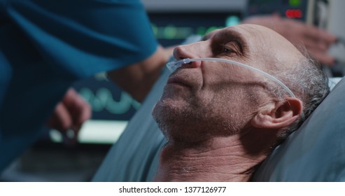 Close-up Shot Of A Nurse Placing Nasal Cannula Into Patients Nose And Heart Monitor With Vital Signs