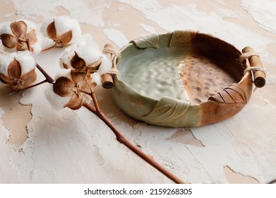 A Closeup Shot Of Old Ceramic Cooking Pot With Dried Cotton Plant N A Table