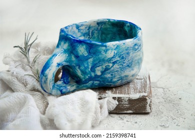 A Closeup Shot Of An Old Ceramic Mug On A Wooden Surface With White Cloth And Rosemary On The Side