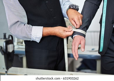 Closeup shot of old-fashioned tailor taking wrist measurements from client in small atelier studio to make custom classic suit with jacket