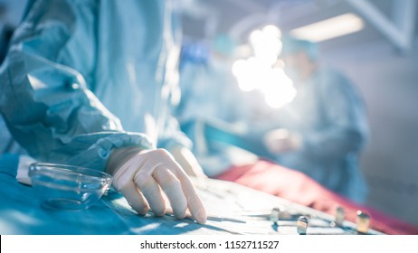 Close-up Shot in the Operating Room of Surgical Table with Instruments, Assistant Takes Instruments for Surgeons During Operation. Surgery in Progress. Professional Medical Doctors Performing Surgery.