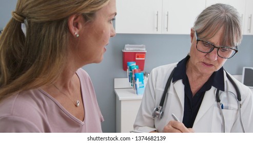 Close-up Shot Of  Patient Talking To Her Primary Care Doctor In Exam Room. Middle-aged Woman Having Appointment With Female Senior Physician