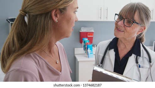 Close-up shot of  patient talking to her primary care doctor in exam room. Middle-aged woman having appointment with female senior physician