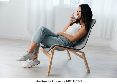 Closeup Shot Of Pensive Young Asian Cute Woman Think About Bad Relationships Drink Water Looks Aside Sit On Chair In Light Office Interior. Breakup From Work. Relaxing Time Concept. Copy Space Offer