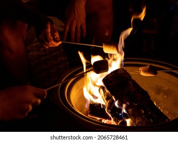 A Closeup Shot Of People Roasting Marshmallows Over A Bonfire