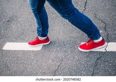 A Closeup Shot Of A Person In Jeans And Red Sneakers Walking On A Road