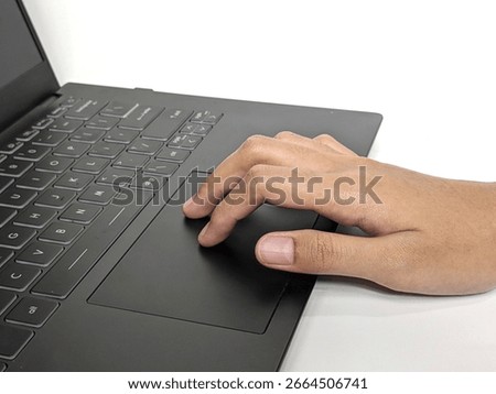 Close-up shot of a person's hand using the touchpad on a modern laptop computer with a black keyboard on a white surface