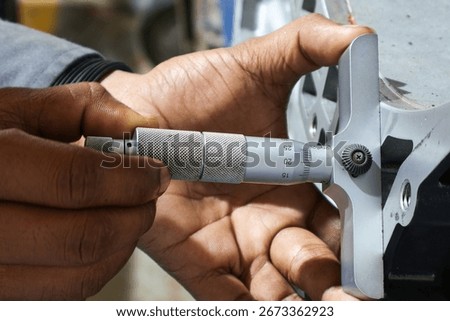 Close-up shot of a person's hands using a depth micrometer to precisely measure a large industrial metal component. The focus is on the intricate process of quality control.