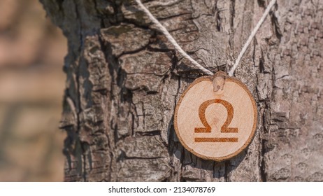 Close-up shot of a piece of wood with a zodiac sign engraved on it, especially the libra sign