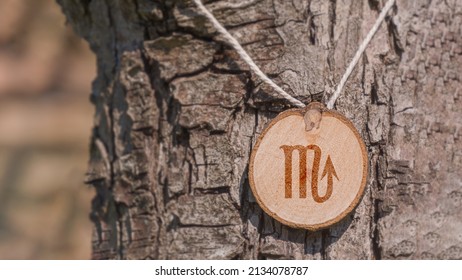 Close-up shot of a piece of wood with a zodiac sign engraved on it, especially the scorpio sign