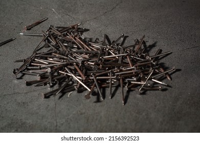 A closeup shot of a pile of old rusty nails on a gray background