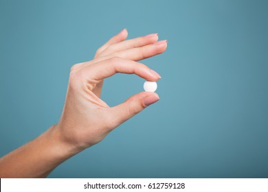 Close-up shot of pill in nurse's hand isolated over blue background.
