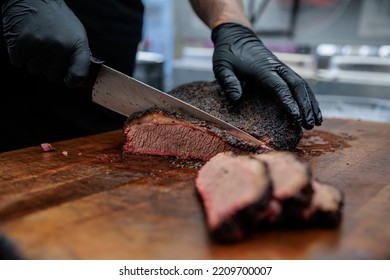 A close-up shot of a pitmaster cleanly slicing through the tender cut of Texas-style beef brisket that will be served at a barbecue (BBQ) restaurant.  - Powered by Shutterstock