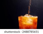 Close-up shot of pouring sparkling water with ice in a glass. placed on a black background