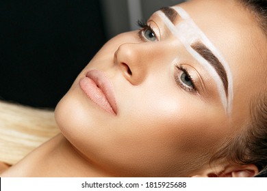 Closeup shot of a pretty woman with brow paste on her brows before permanent makeup 