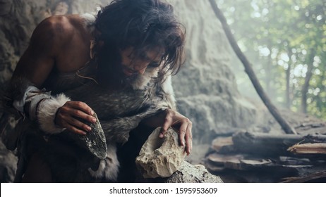 Closeup Shot of Primeval Caveman in Animal Skin Hits Rock with Sharp Stone, Makes First Primitive Tool for Hunting Animal Prey. Neanderthal Using Flint Rock. Dawn of Human Civilization.
