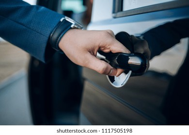 Close-Up Shot of a Professional Businessman with his Hand Firmly on the Car Door Handle, Demonstrating Elegance and Confidence while Opening the Door to his Vehicle