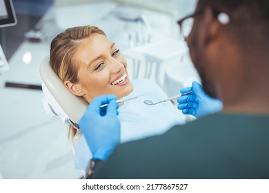 Closeup Shot Professional Dentist With Protective Surgical Mask, Doing Check Up Of Patient. Dentist Examining Smiling Female Patient In Clinic. Male Is Checking Smiling Patient In Examination Room.