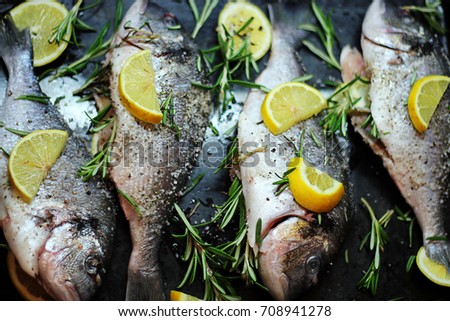 Close-up shot of raw fish with lemon ready for cooking. Sparus aurata. Concept of healthy food. Recipe of gilt-head bream fish.
