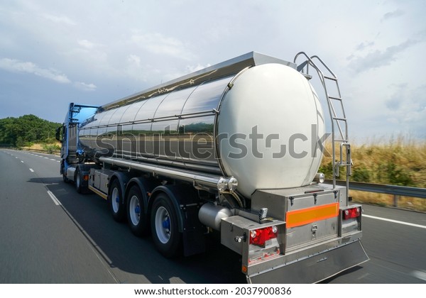 a closeup shot of rear tanker truck on\
highway road by dense forest at\
daylight
