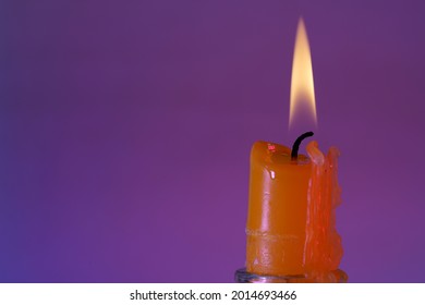 A closeup shot of a red candle with flame isolated on purple background with copyscape
