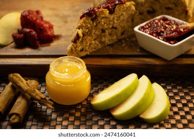 Close-up shot of a rustic bread loaf with a slice cut out, topped with berry compote. The setup includes fresh green apple slices, a jar of honey, and a wooden spoon dipped in berry compote, placed on - Powered by Shutterstock