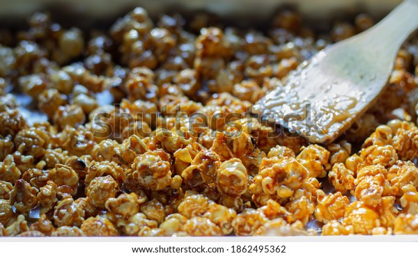 Close-up shot selective focus at heap popcorn of\
golden caramel popcorn made from corn in a yellow with spoon wooden\
delicious gourmet crunchy snack food or snack for homemade or\
entertain movie.