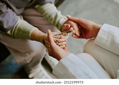 Close-up shot showing healthcare professional assisting a child with a prosthetic hand, demonstrating support and care during medical check-up without showing any facial details - Powered by Shutterstock