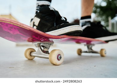 Close-up shot of skateboarder's feet on pink skateboard at skate park. Teenager is skateboarding. Leisure activity and extreme sport concept - Powered by Shutterstock