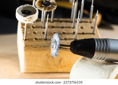 A close-up shot of a small drill with an attachment and a polishing wheel, taken in a goldsmith workshop. The focus is on the drill bit - Shutterstock ID 2273756135