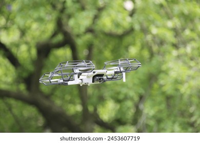 Closeup shot of a small drone hovering at eye level against a blurred backdrop in a park setting