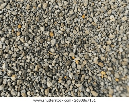 Close-up shot of small, irregularly shaped gravel stones with various shades of gray, beige, and brown, creating a textured, natural surface.