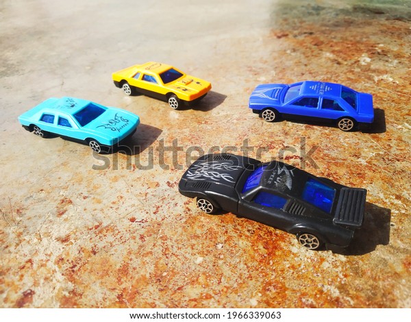 A closeup shot of small toy cars on a brown
concrete surface