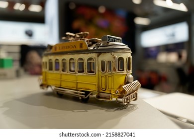 A Close-up Shot Of A Small Yellow Toy Bus With Blurred Background