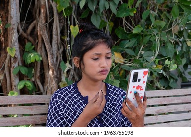 A Closeup Shot Of A South Asian Female During A Video Call On A Bench