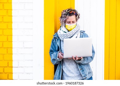 A Closeup Shot Of A Spanish Woman Wearing A Face Mask With A Laptop On A Colorful Wall Background