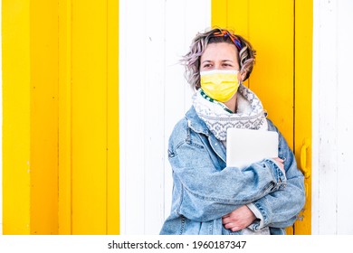 A Closeup Shot Of A Spanish Woman Wearing A Face Mask With A Laptop On A Colorful Wall Background