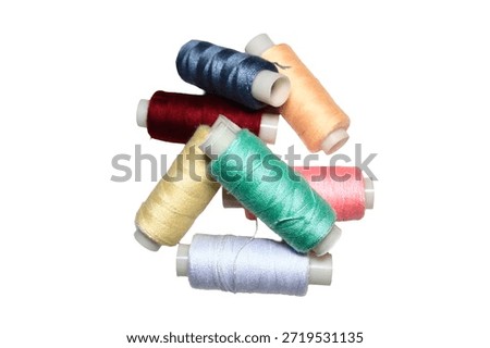 Close-up shot of a stack of thread spools on a clean white surface, suitable for use in illustrations about sewing, crafting, or textiles.