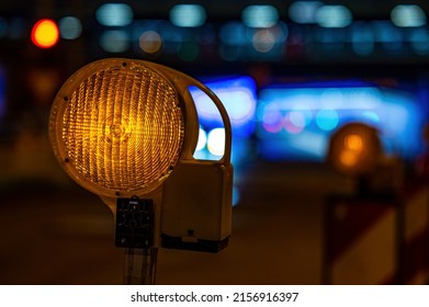 A Closeup Shot Of A Street Barricade With Warning Signal Lamp On A Night Road With Blurred Background 