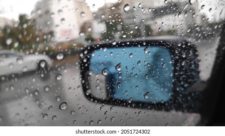 A closeup shot of the surface of a mirror with raindrops against a blurred background
