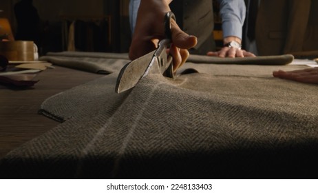 Close-up shot of tailor cutting textile according to sketch using scissors for sewing. Process of making clothes in luxury designer atelier or tailoring studio. Fashion and hand craft concept. - Powered by Shutterstock