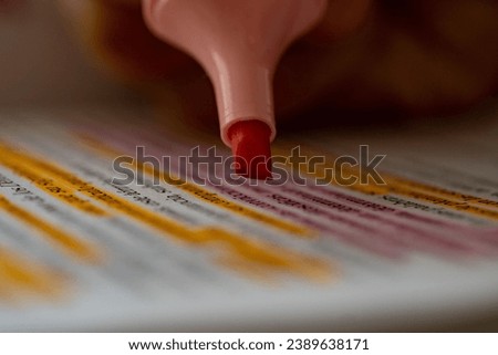 A closeup shot of taking notes with a pink highlighter pen with the blurred background