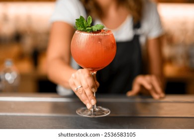 Close-up shot of a tall glass with a cold orange cocktail with mint leaves - Powered by Shutterstock