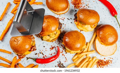 A Closeup Shot Of Tasty Smash Burgers, French Fries, And Red Spicy Peppers On The White Background