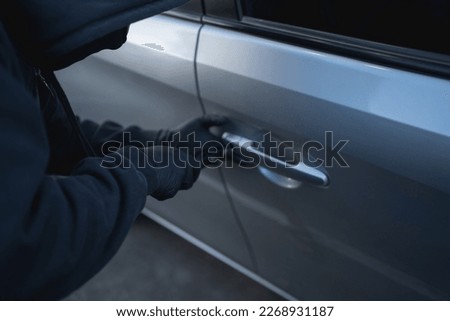 Close-up shot of a thief stealing a car with a screwdriver. car theft concept