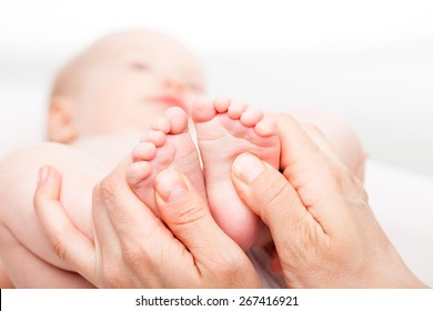 Close-up shot of three month baby girl receiving foot massage from a female massage therapist. Camera is focused on infant's feet. Face is blurred in background. - Powered by Shutterstock