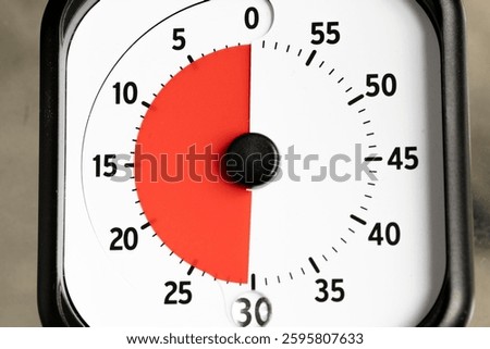 Close-up shot of a timer set to 30 minutes. The dial features a red section indicating the time elapsed, against a white background with black numbers.